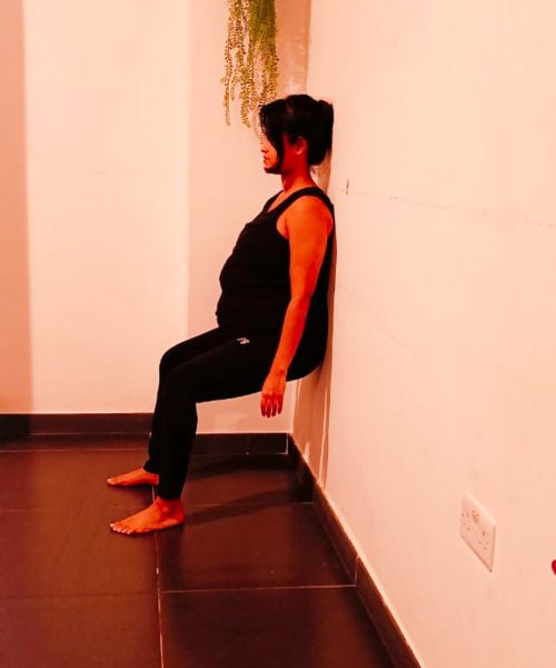 PRENATAL YOGA CHAIR POSE Image of a pregnant lady practicing Chair Pose